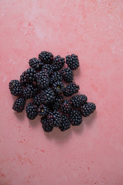 A bunch of ripe, organic blackberries on a vibrant pink surface, showcasing freshness and natural beauty.