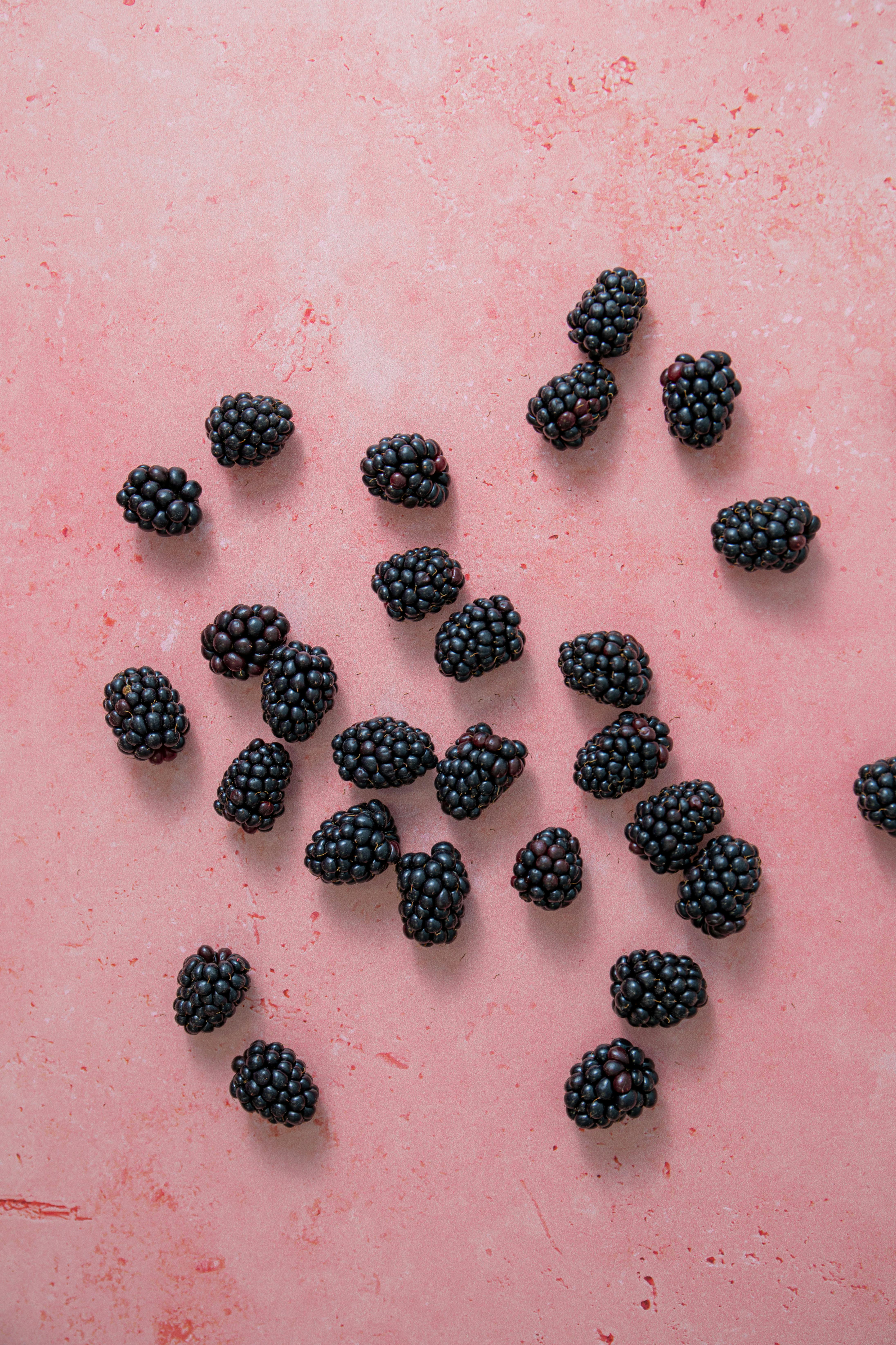 Ripe blackberries scattered on a vibrant pink surface, offering a perfect blend of contrast and freshness.