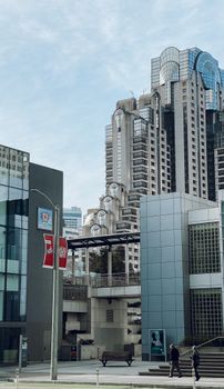 Futuristic buildings with glass facades in a bustling city downtown under clear skies.