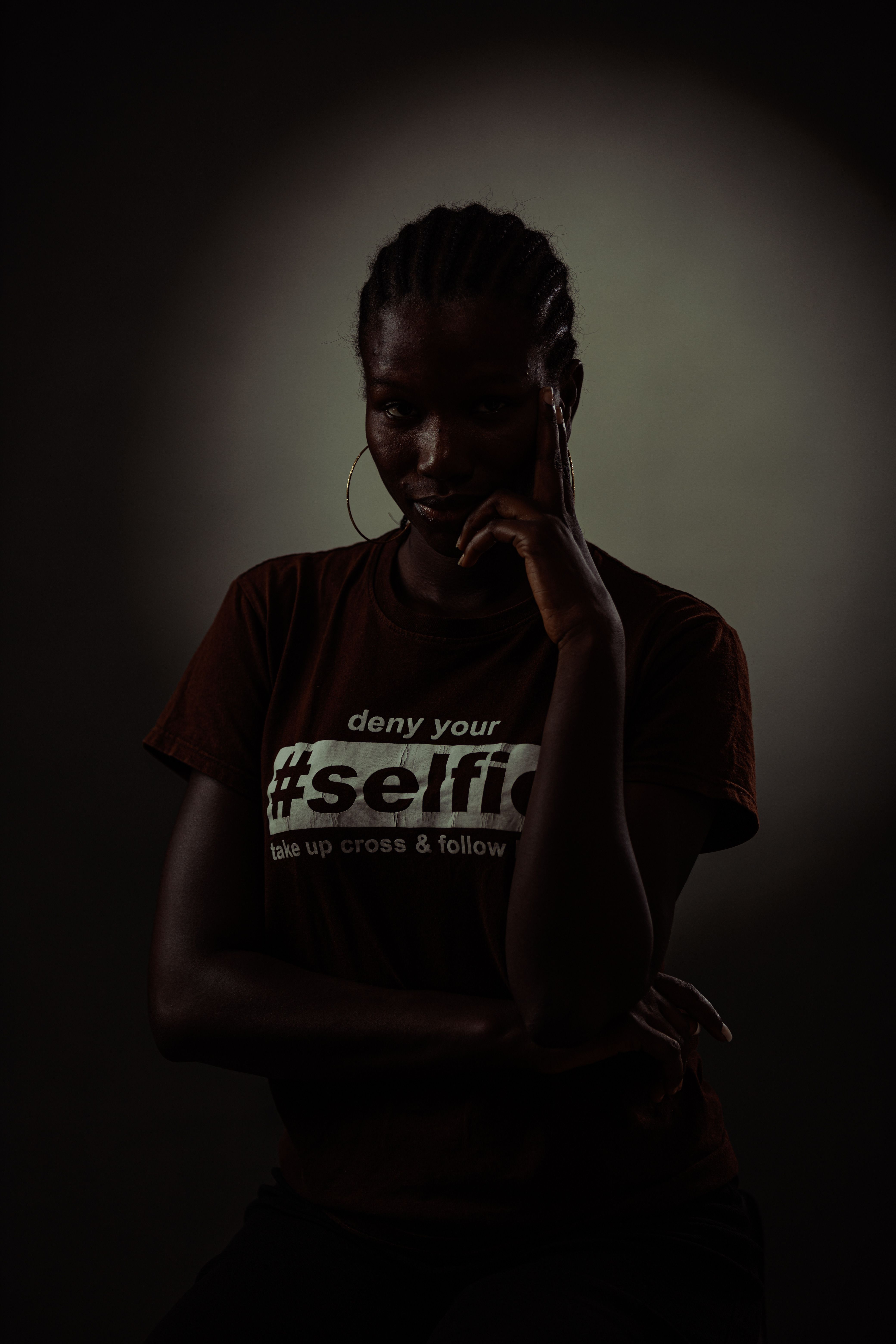 Dramatic studio portrait of woman in dark moody lighting showcasing t-shirt message.