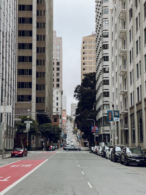 Free Urban street in downtown San Francisco with a bus lane, lined with skyscrapers and parked cars. Stock Photo