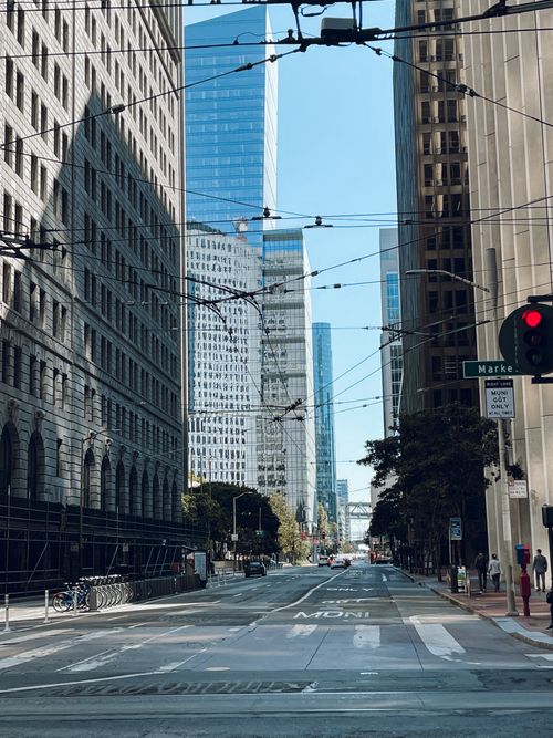 Free A bustling urban street flanked by tall modern skyscrapers under a clear blue sky. Stock Photo
