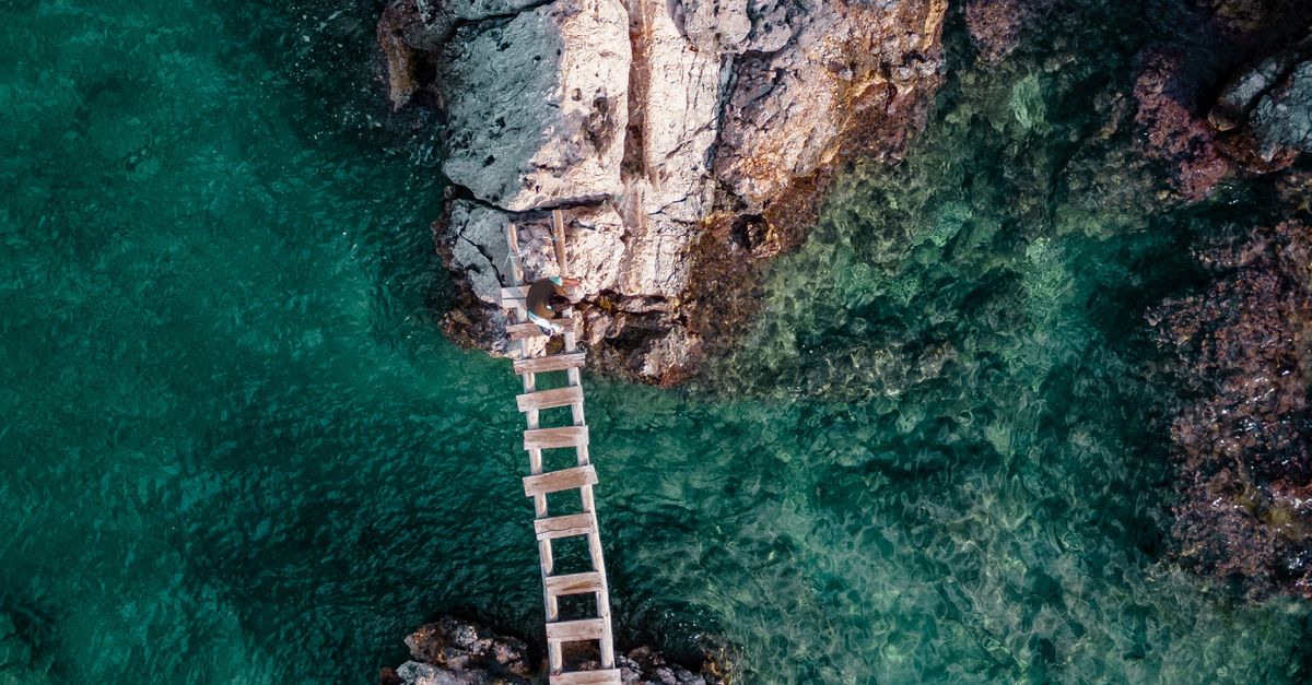 Bridge Between Rocks Drone Shot of a Wooden Bridge between Rock Formations on the Shore at ...