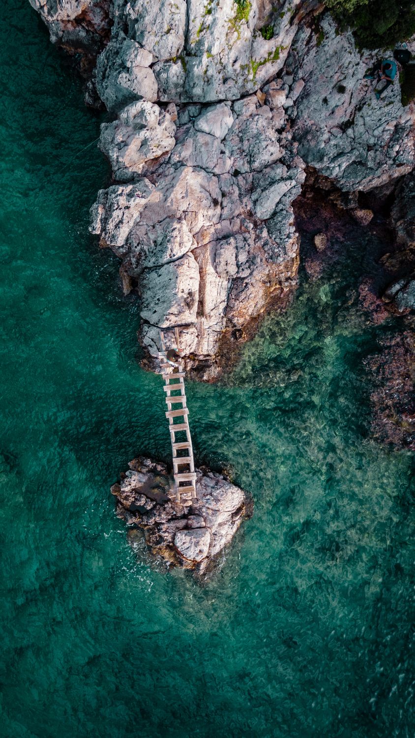 Bridge Between Rocks Drone Shot of a Wooden Bridge between Rock Formations on the Shore at ...