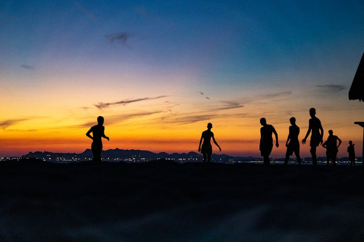 Silhouettes Of Boys Exercising On A Beach At Dusk