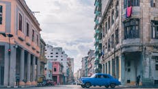 哈瓦那迷人的城市场景中，老式建筑和经典的蓝色汽车在晴朗的天空下格外醒目