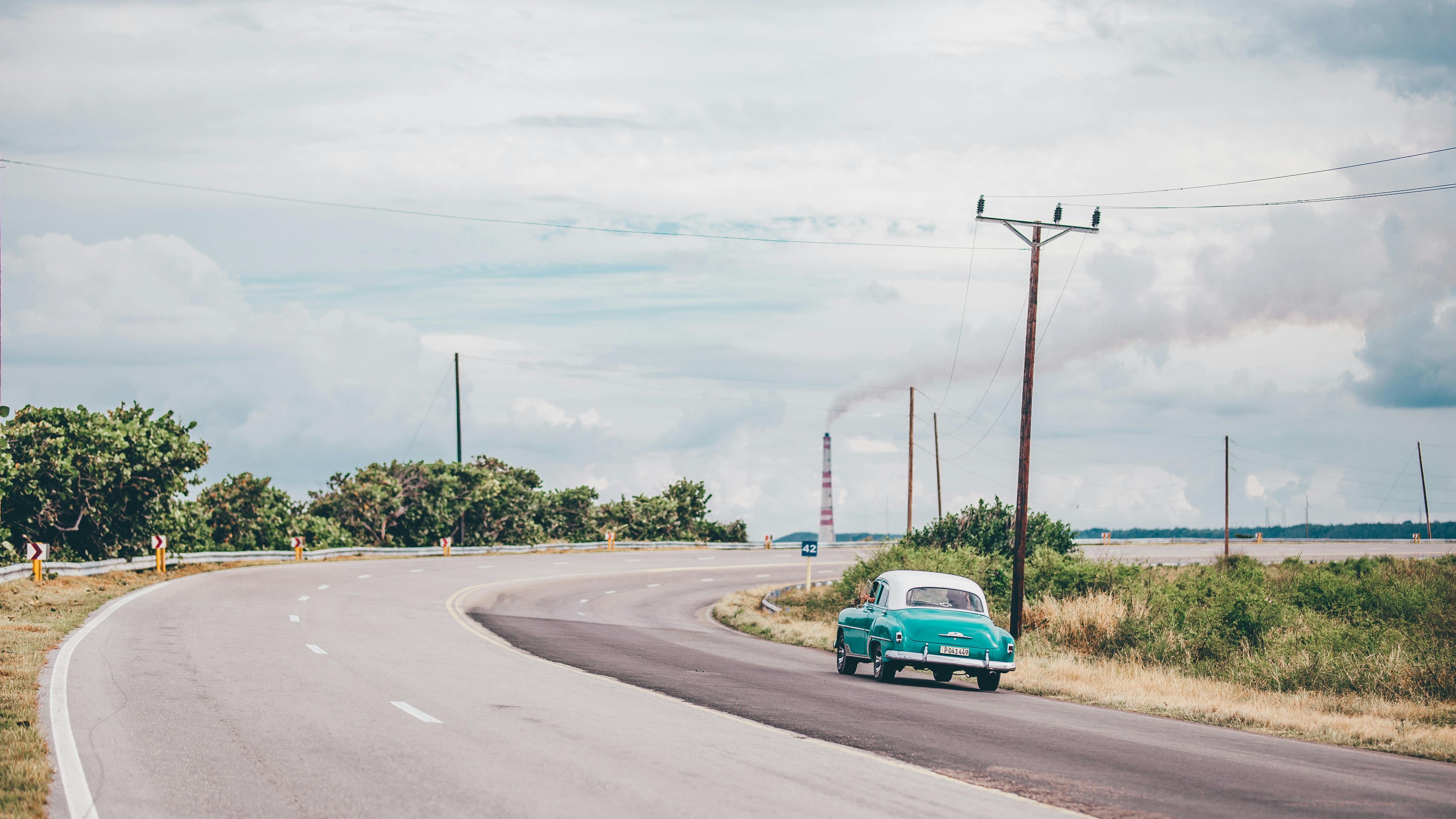 一辆经典古董汽车行驶在古巴玛雅贝克风景优美的沿海公路上