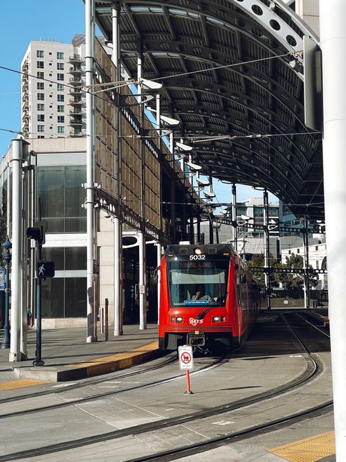 Free Red tram approaching a San Diego urban transit station under a modern architectural canopy. Stock Photo