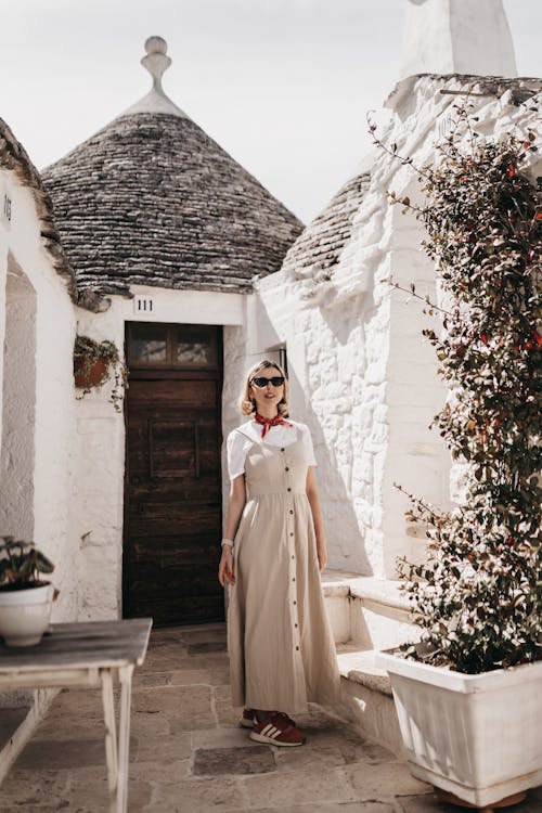 Woman in Gray Dress Standing in front of a Trulli in Alberobello