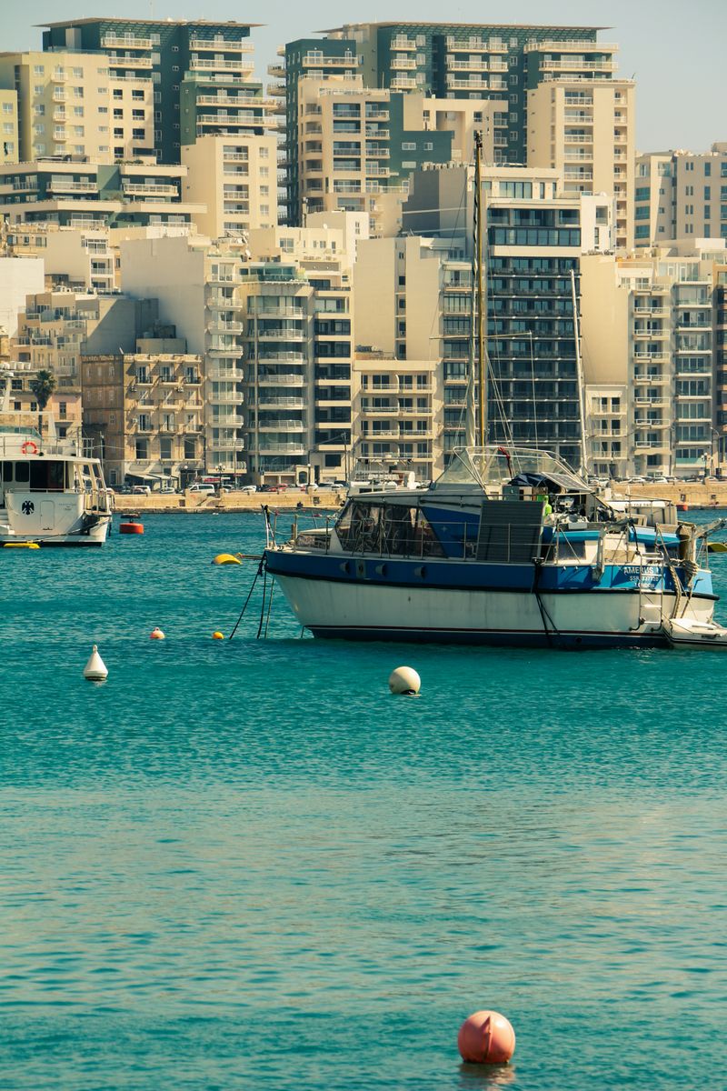 Boats anchored along a Maltese waterfront with apartments behind