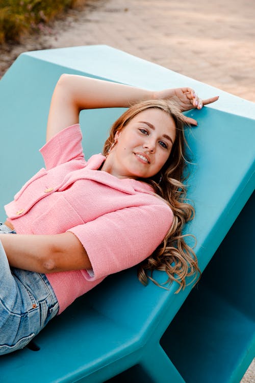 Young Woman in a Pink Top Lying on a Lounge Chair