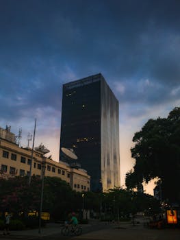 A modern skyscraper reflects the fading daylight in a bustling urban environment.