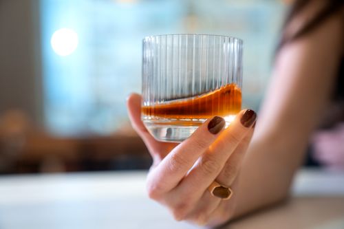 Free Elegant close-up of a glass of whiskey in hand, showcasing indulgence and luxury. Stock Photo
