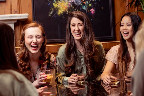 Smiling Women Sitting Together by Table