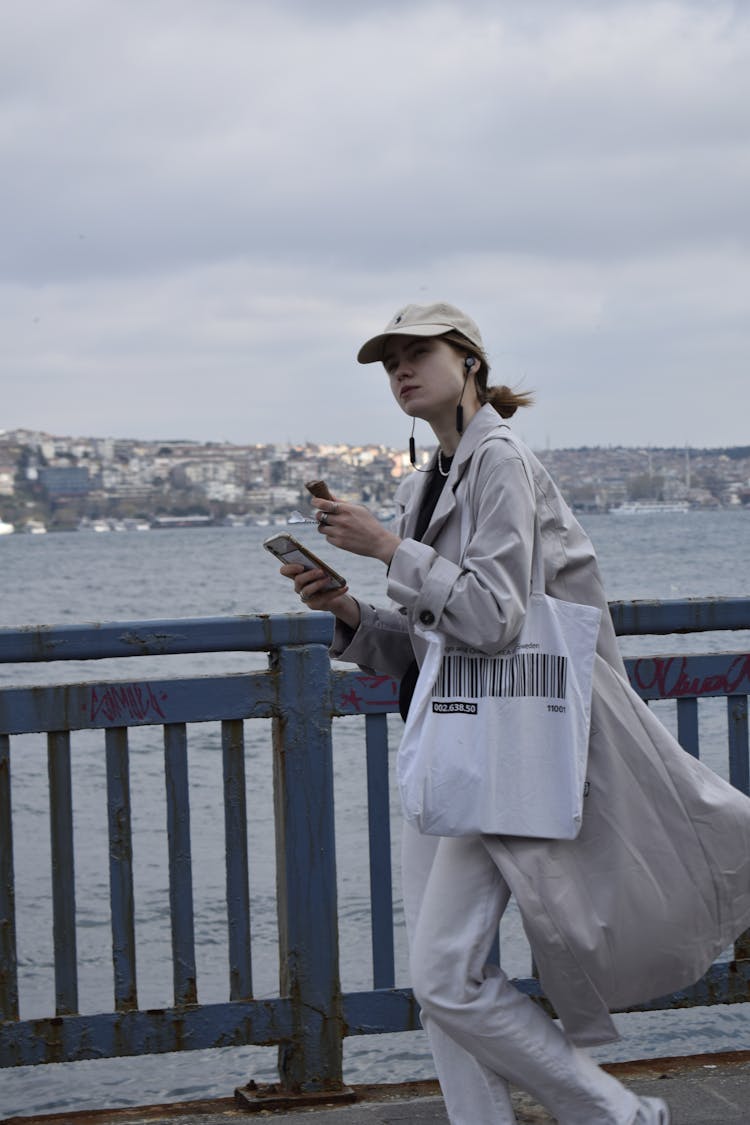 Young Woman Walking With A Smart Phone In Hand And Headphones 