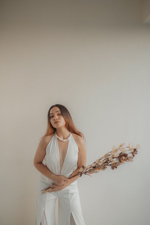 Free Stylish woman in white holding dried flowers against a minimal background. Stock Photo