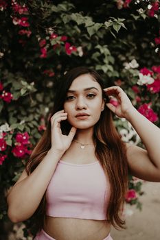 Fashion portrait of a woman amidst vibrant pink flowers, exuding elegance.