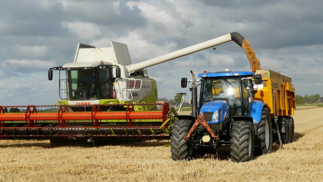 Blauer Traktor Neben Dem Weißen Landwirtschaftlichen Fahrzeug Tagsüber