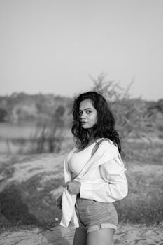 Black and white portrait of a woman posing outdoors in a relaxed style.