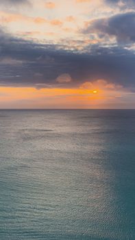 Captivating view of a serene ocean during sunrise, capturing tranquil waters under a dramatic sky.
