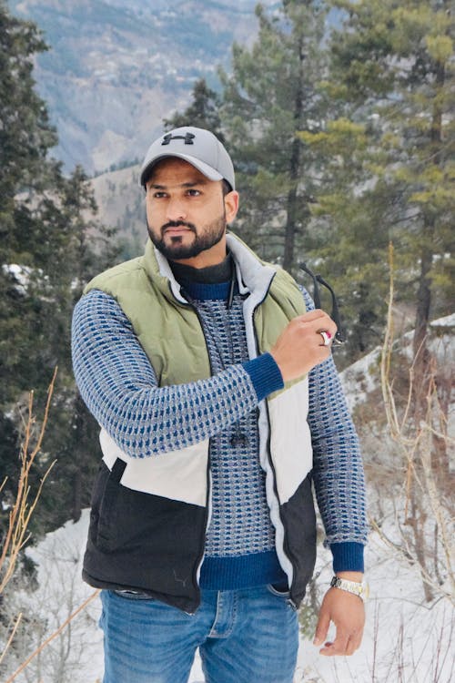 Man in Cap and Vest Posing in Forest in Winter