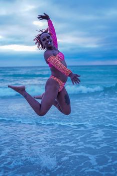 Woman with colorful swimwear joyfully jumps on Clearwater Beach, Florida.