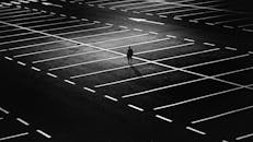 广阔的夜间停车场中，一个孤独的身影形成剪影