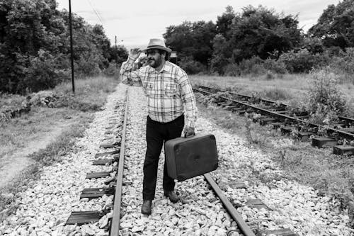 Man in Shirt and with Suitcase on Railway Tracks