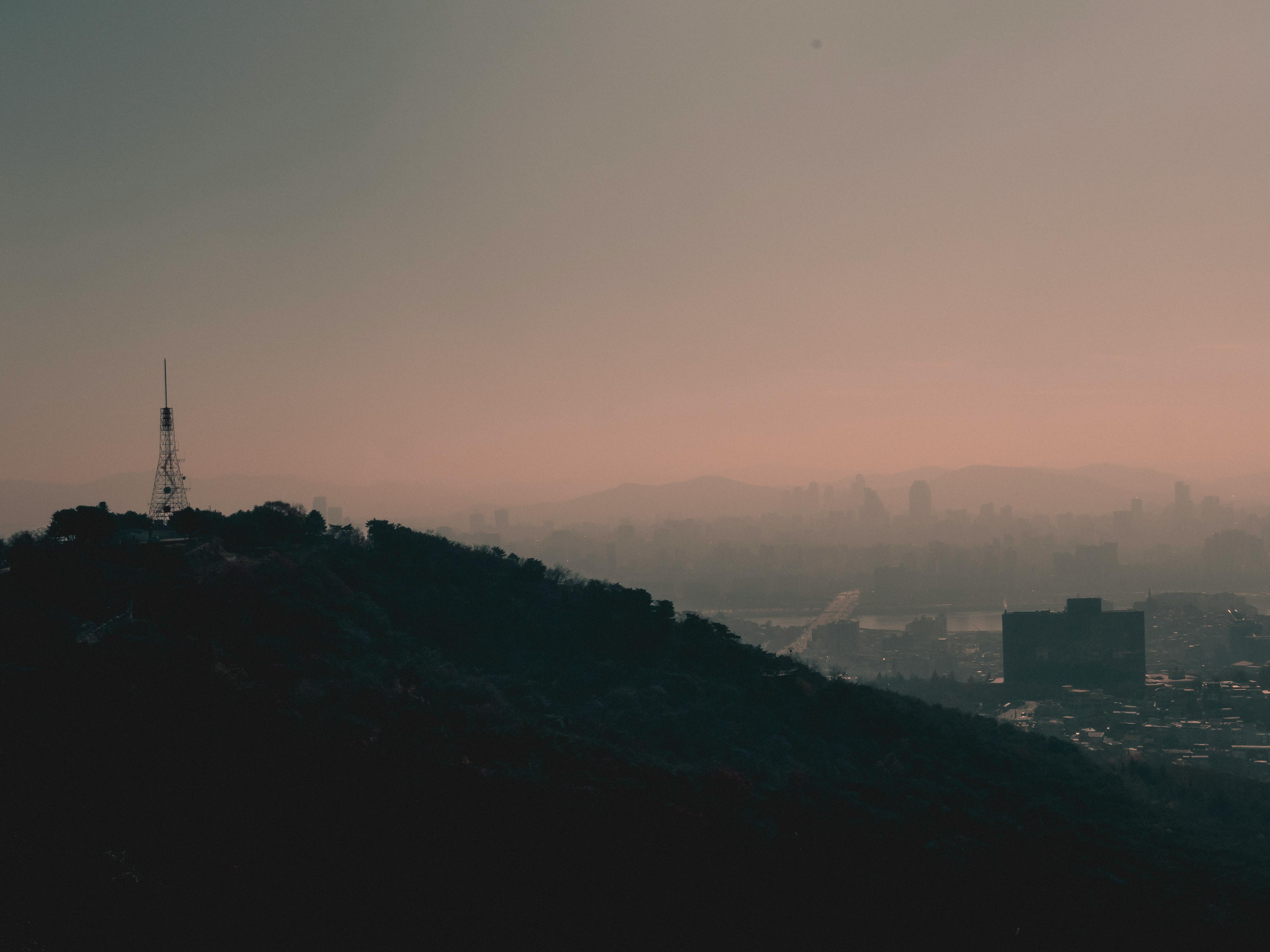 黄昏时分，薄雾笼罩着宁静的城市，山丘与城市轮廓若隐若现