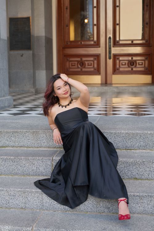 Free Chic woman in a black dress sitting on stairs, highlighting urban elegance. Stock Photo