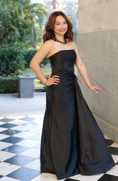 Free Beautiful woman in an elegant black dress posing confidently outdoors. Stock Photo