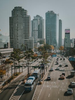 城市街景中，晴朗的天空下矗立着摩天大楼，车流穿梭不息