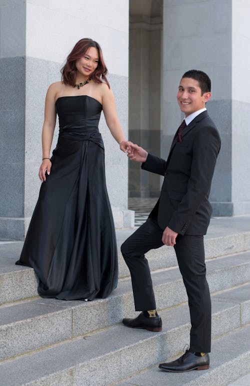 Man in Suit and Woman in Black Dress Holding Hands