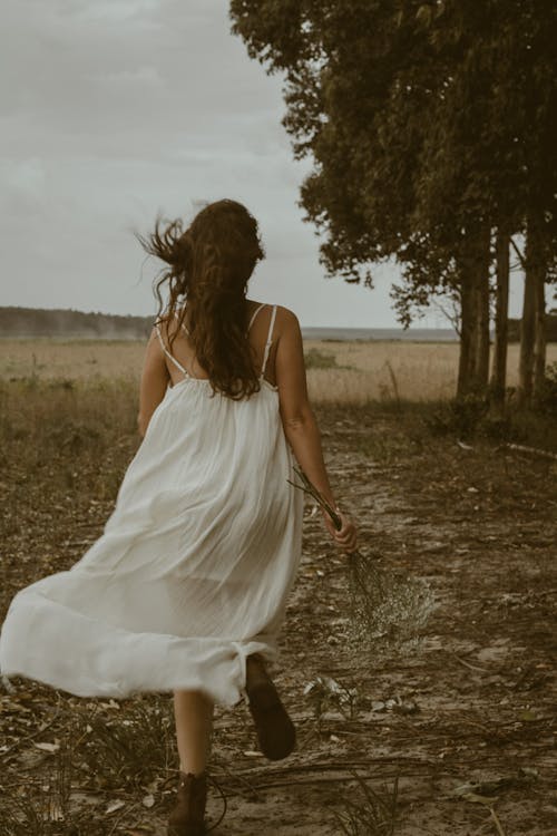 Woman in White Dress Running on Meadow