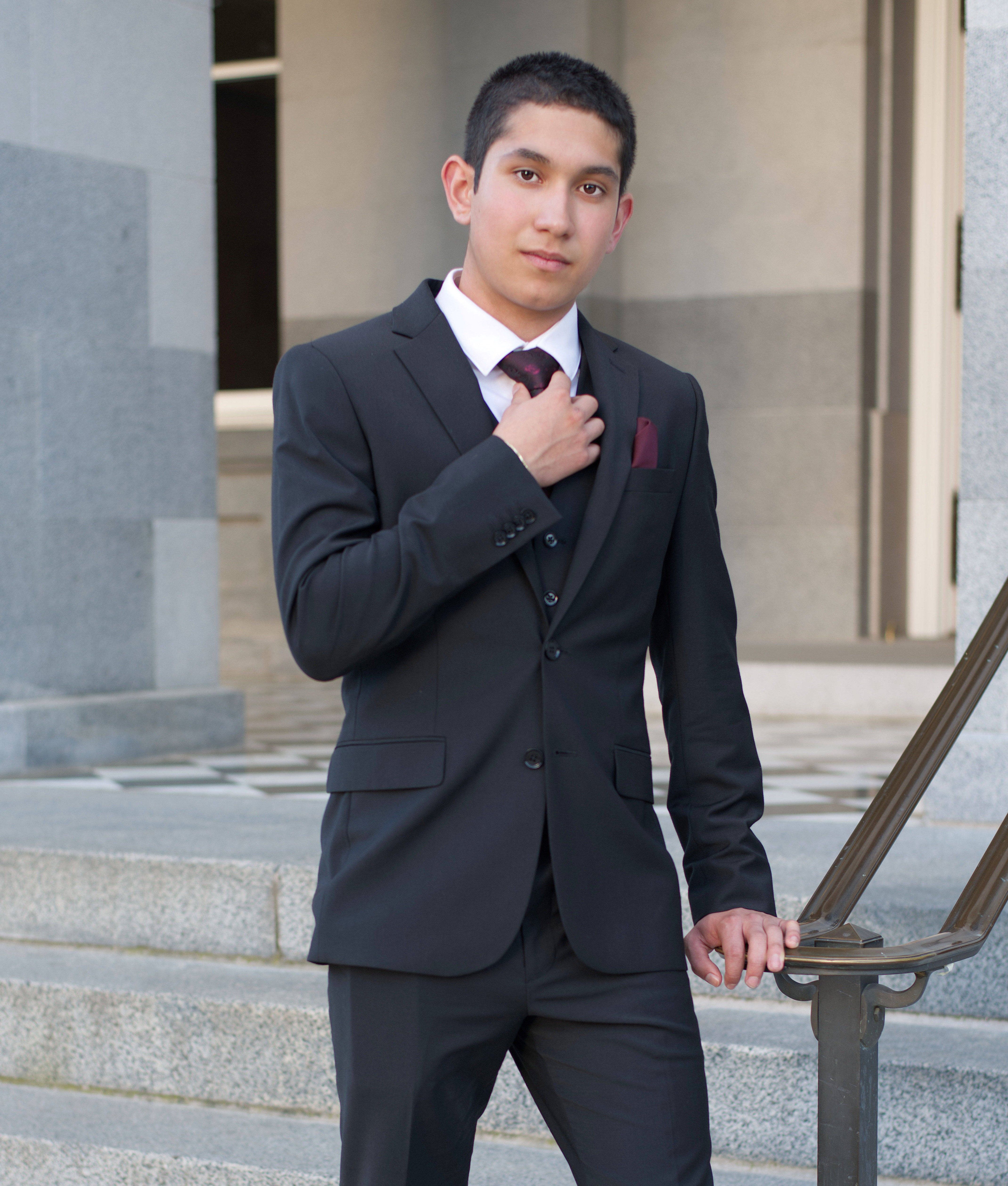 Confident young man in a suit posing on urban stairs, embodying modern elegance.