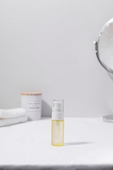 Minimalist still life of a cosmetic oil bottle with a mirror reflecting elegance.