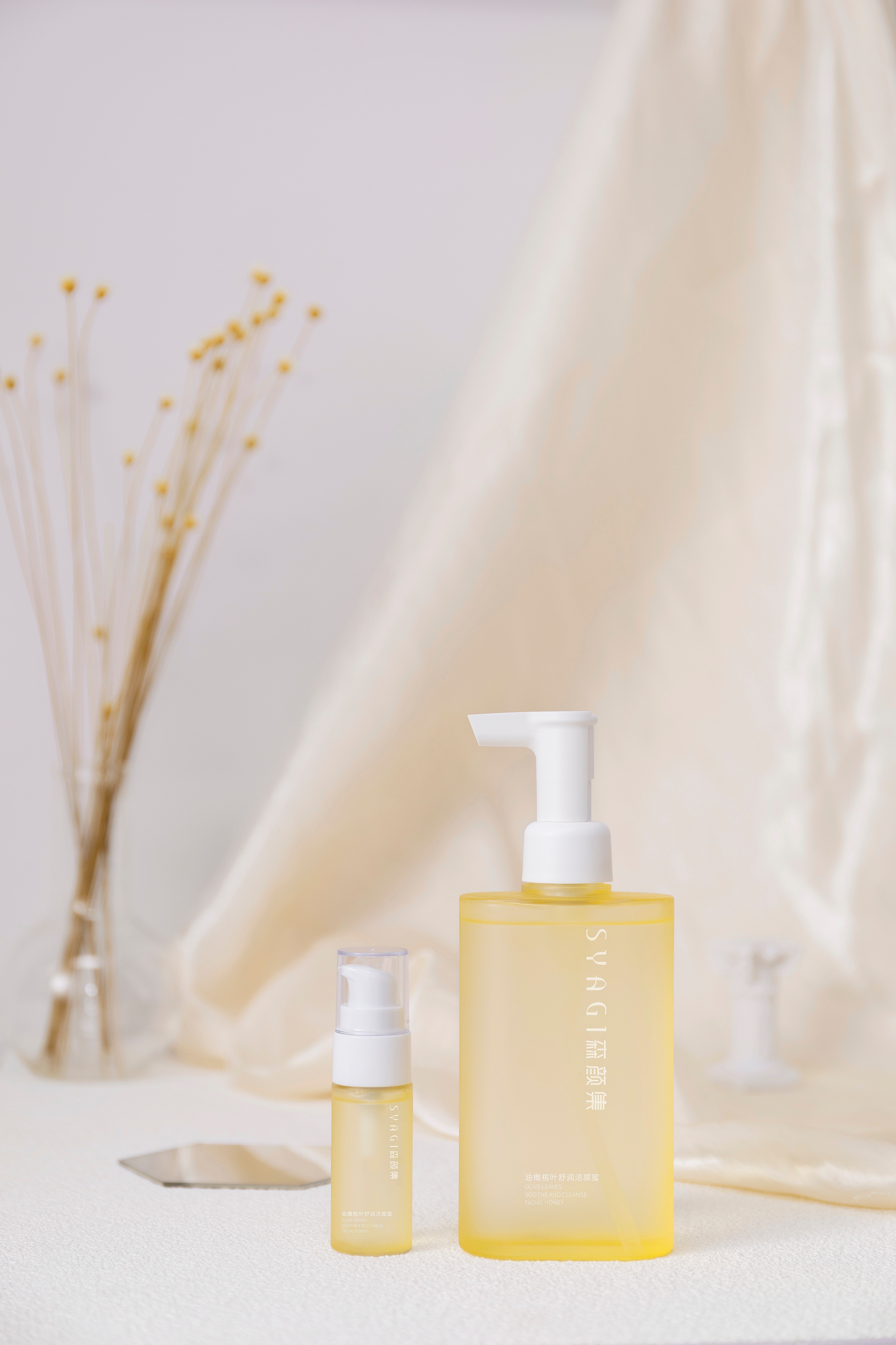 Elegant skincare bottles with dry flowers on a neutral backdrop for minimalist cosmetic branding.