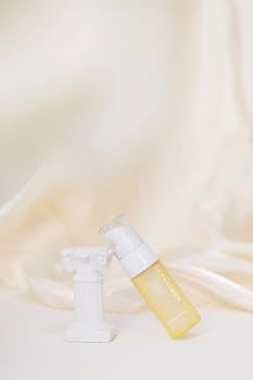 Yellow cosmetic pump bottle elegantly displayed on a mini marble column with a soft cream background.