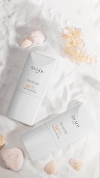 Flat lay of sunscreen tubes surrounded by shells, ideal for skincare and beach themes.