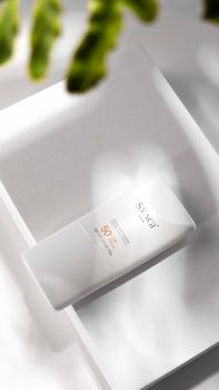 Close-up of a minimalist SPF 50 sunscreen bottle with shadows.