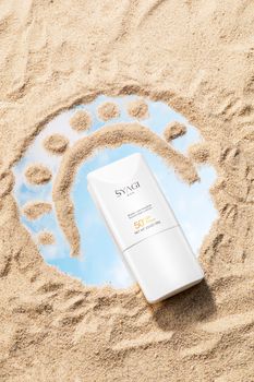 Sunscreen bottle on sand with SPF 50 for sun protection