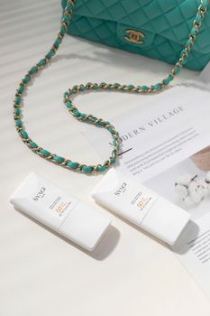 Chic shot of SPF 50 skincare bottles with turquoise bag and magazine layout.