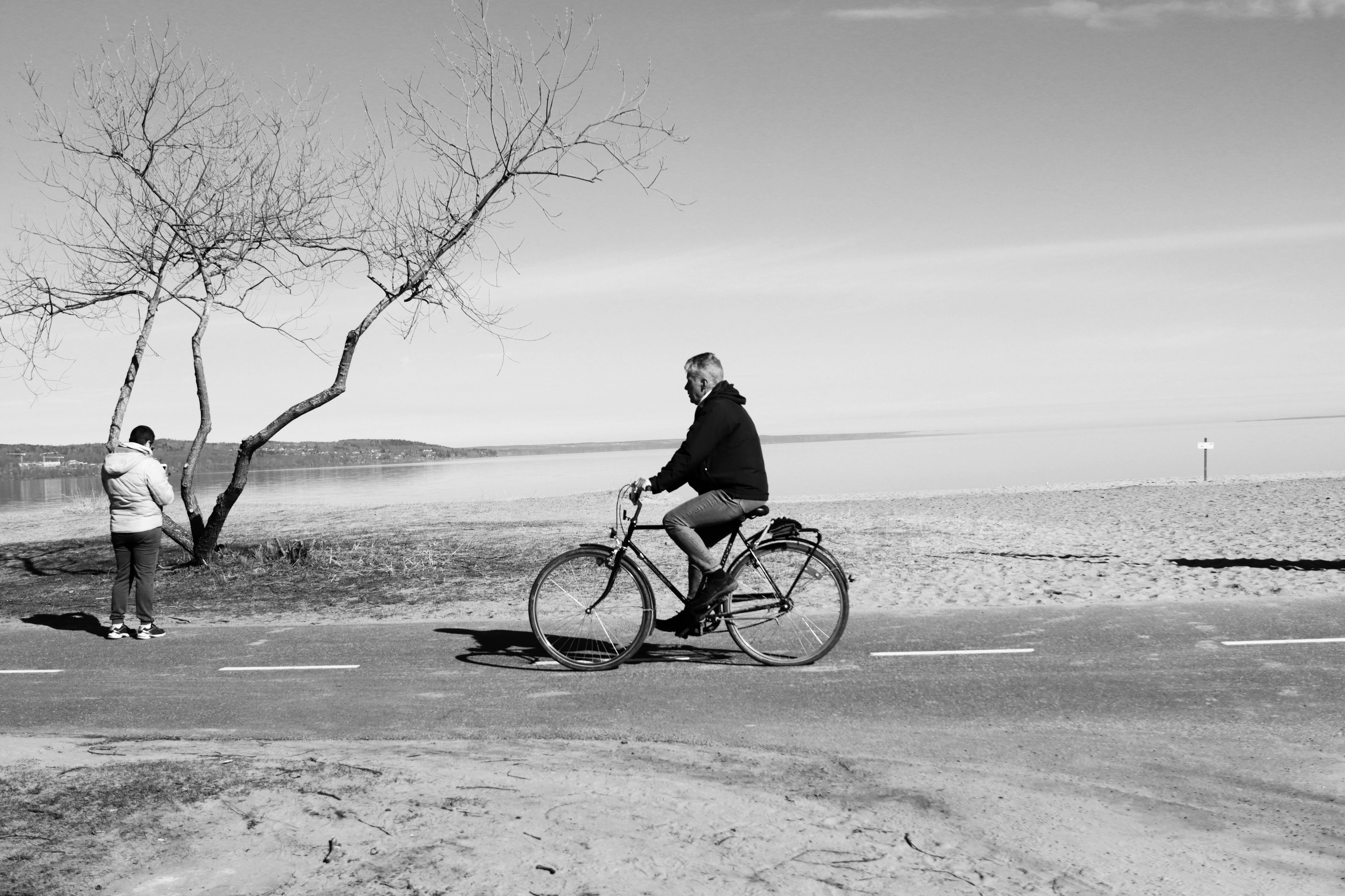 A cyclist rides along a serene beach in Jönköping, Sweden, capturing a peaceful moment.