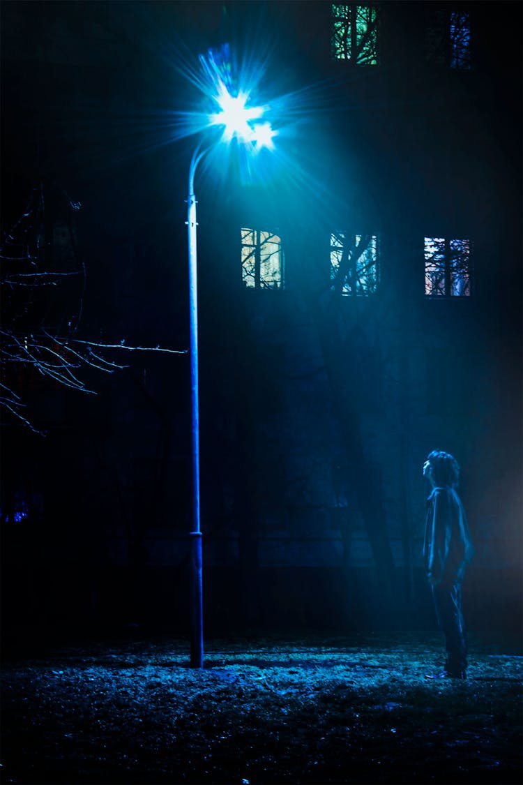 Man Standing In Front Of Street Light Turned On