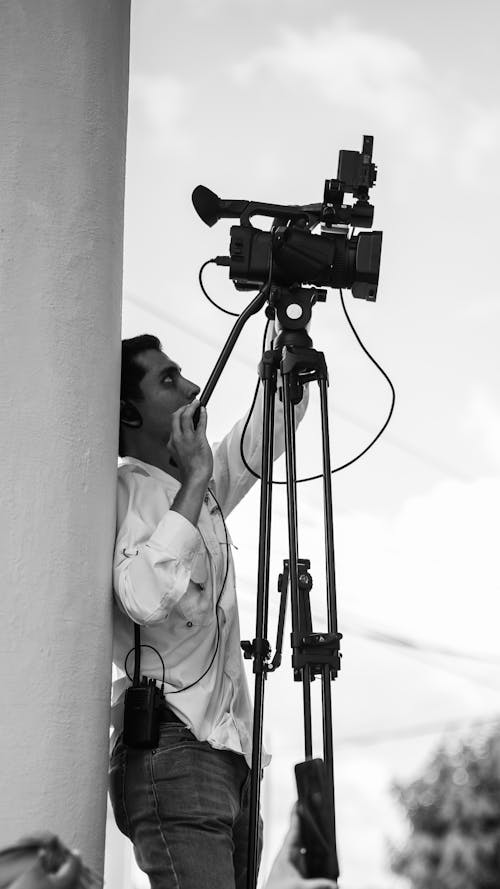 Black and White Photo of a Man Operating a Camera 