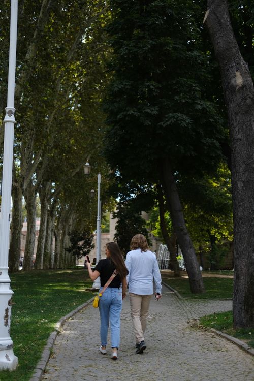 Free A couple leisurely walks through a park in Istanbul, Türkiye on a sunny summer day, capturing a serene moment. Stock Photo