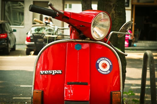 Red Vespa Motor Scooter Parked Near Tree during Daytime