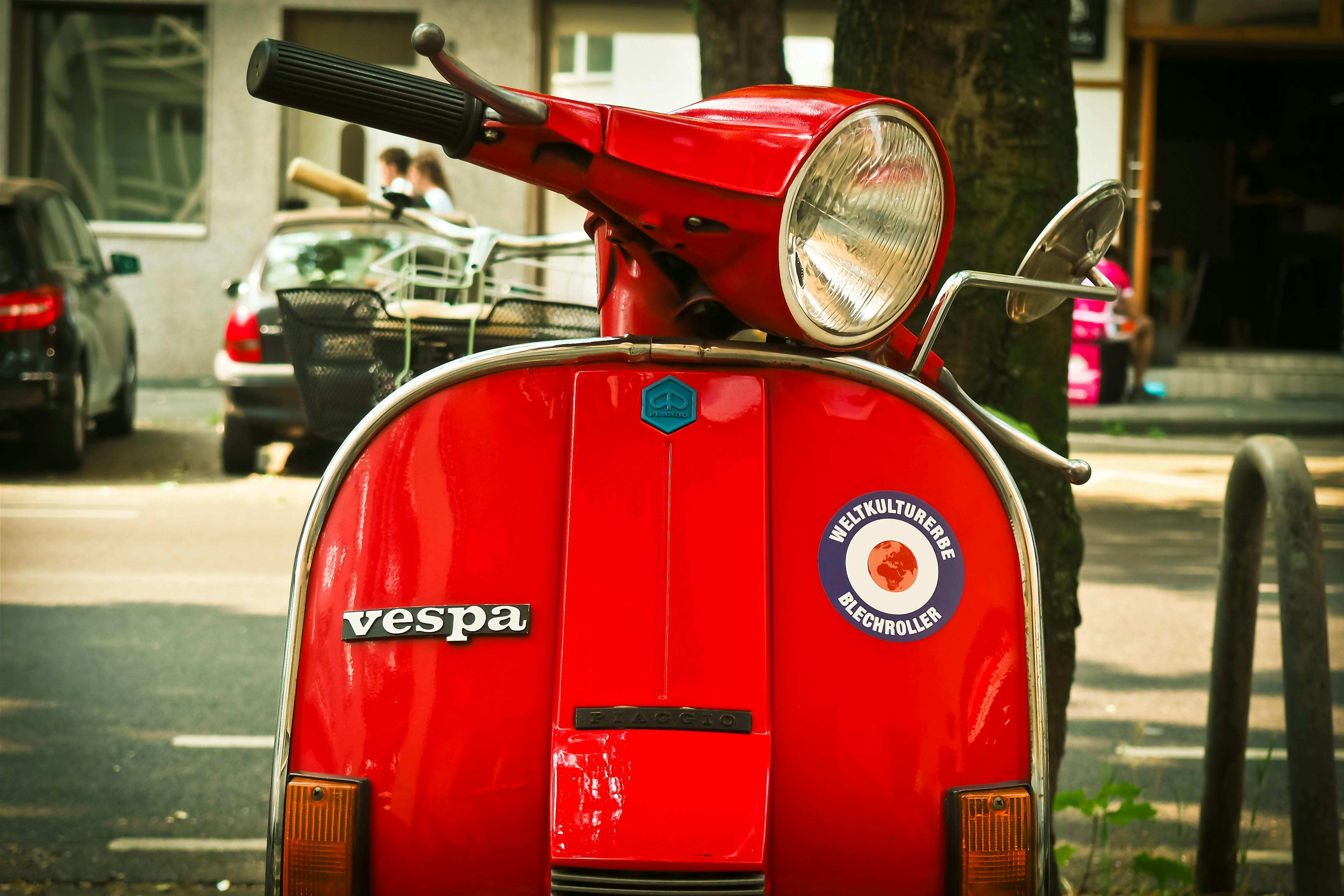 red vespa motor scooter parked near tree during daytime free stock