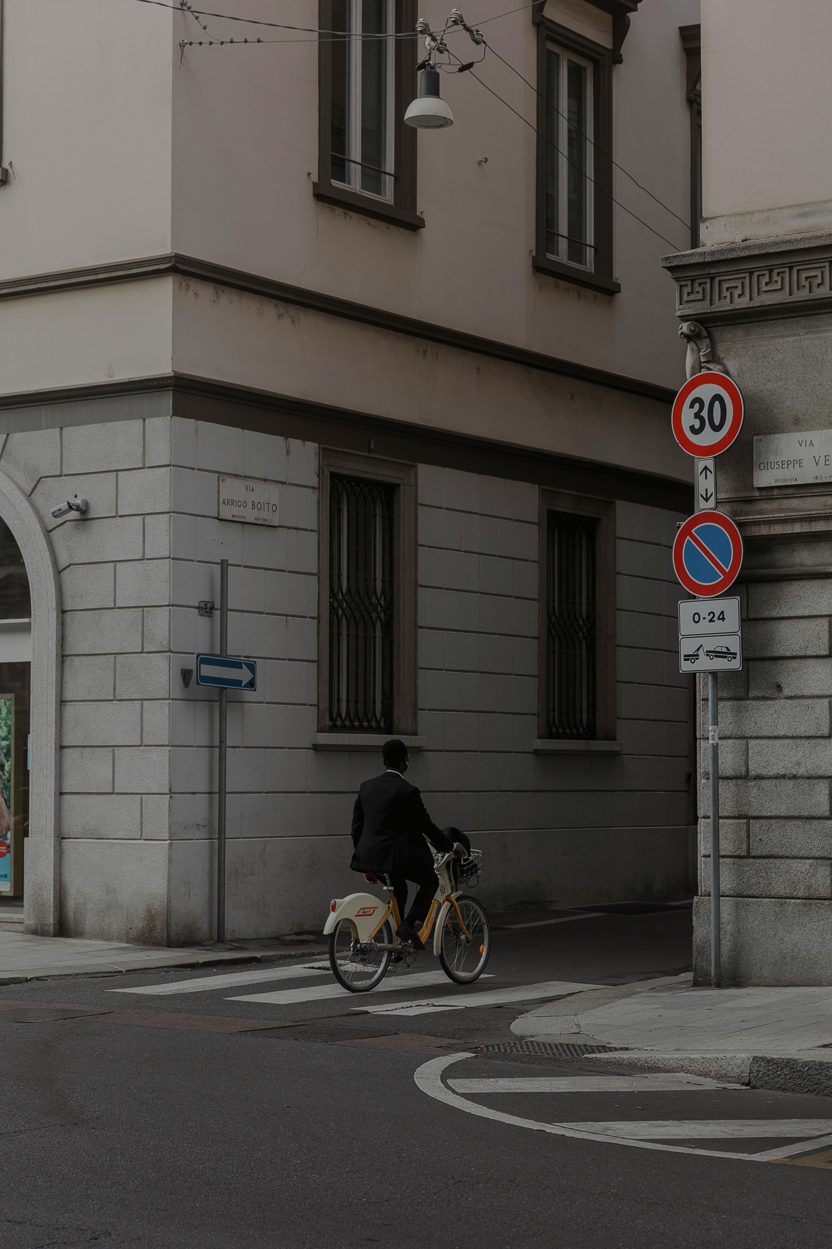 Free A lone cyclist rides on a city street, surrounded by historic architecture and signage. Stock Photo