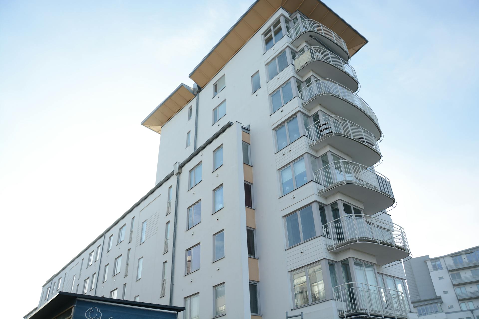 Low angle shot of a contemporary urban apartment building with multiple balconies under a clear blue sky.